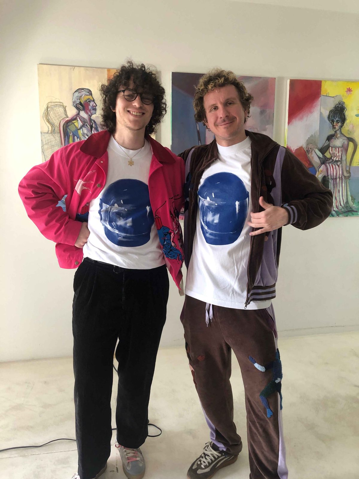 Emanuel Nation and Colm Dillane standing together in a gallery, both wearing matching printed tees